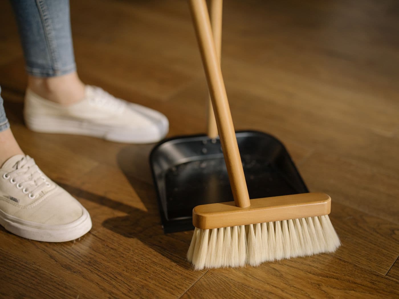 Gros plan d’un balai et d’un porte-poussière sur un plancher de bois franc