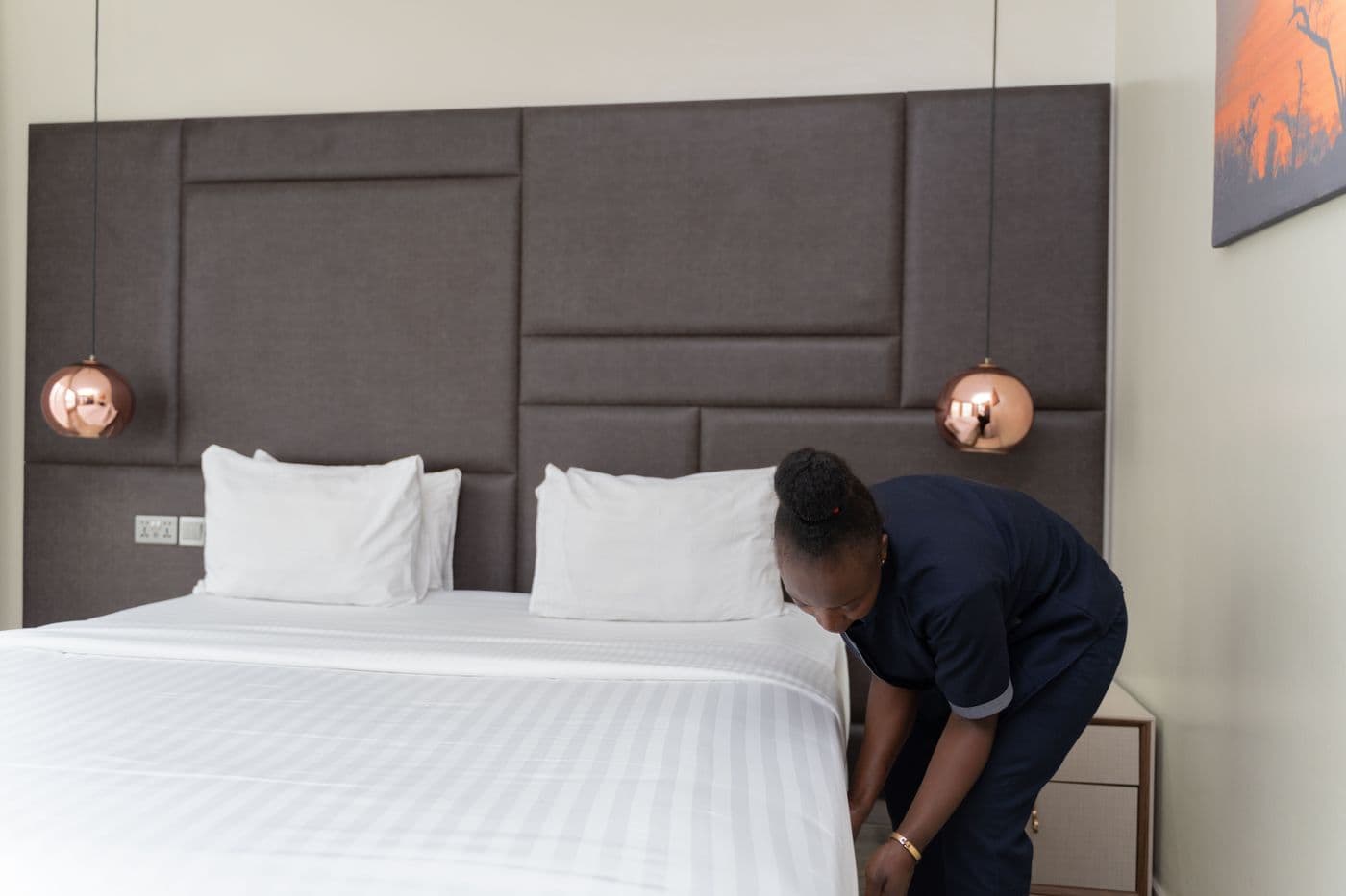 Préposée à l’entretien faisant un lit avec des draps blancs pour les prochains invités