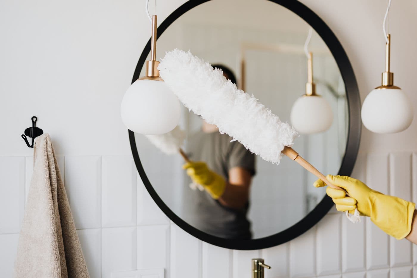 Dépoussiérage minutieux d’un miroir et de luminaires de salle de bain