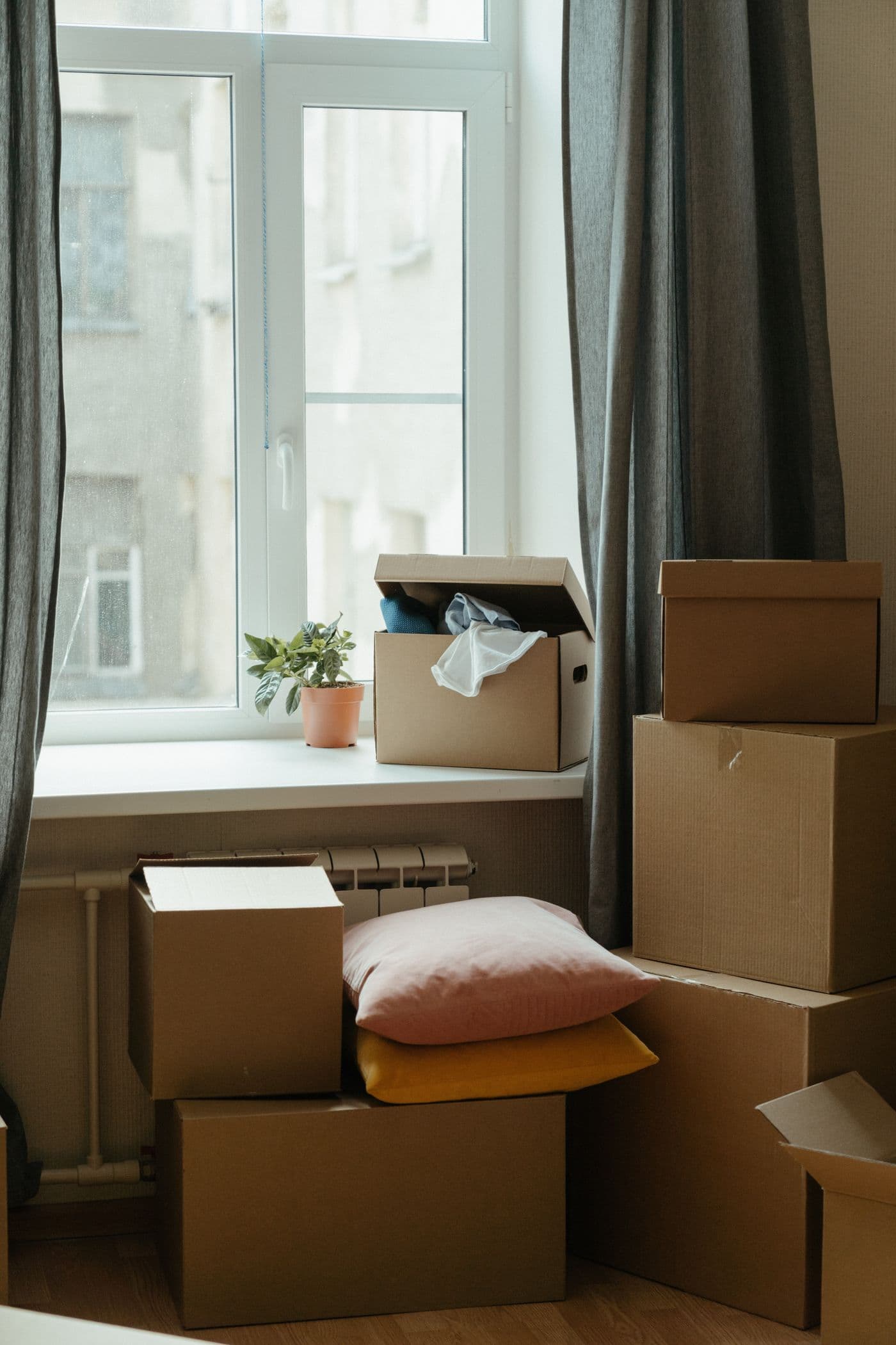 Boîte de déménagement sur un lit fraîchement fait dans une chambre propre et lumineuse